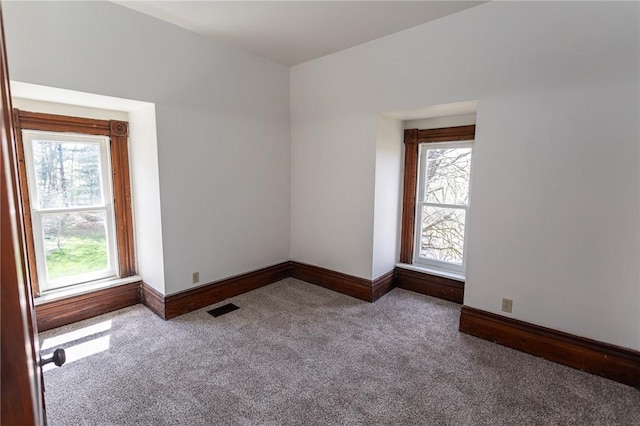 carpeted empty room with a wealth of natural light, visible vents, and baseboards