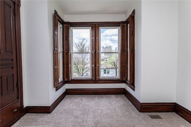 carpeted empty room featuring baseboards