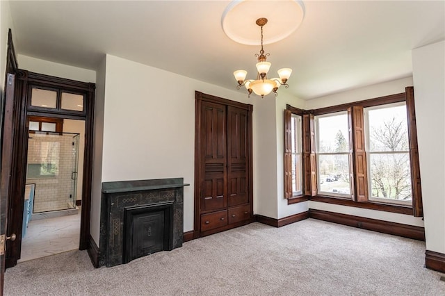 unfurnished living room featuring a chandelier, baseboards, and carpet floors