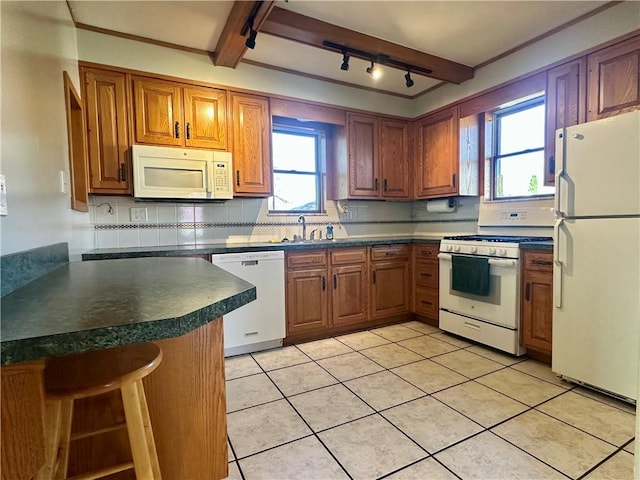 kitchen featuring tasteful backsplash, dark countertops, white appliances, and brown cabinetry