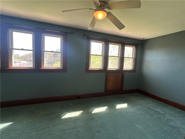 carpeted spare room featuring ceiling fan and baseboards
