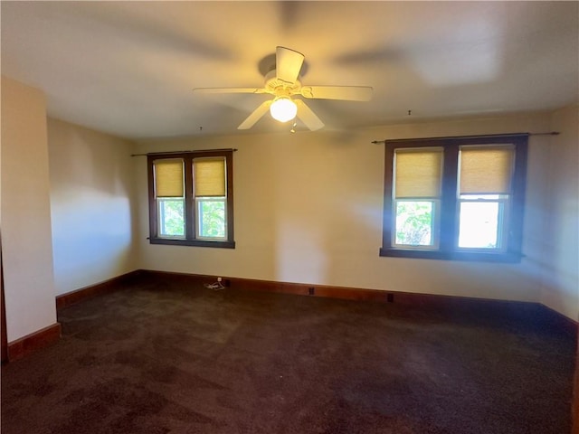 carpeted spare room featuring baseboards and a ceiling fan