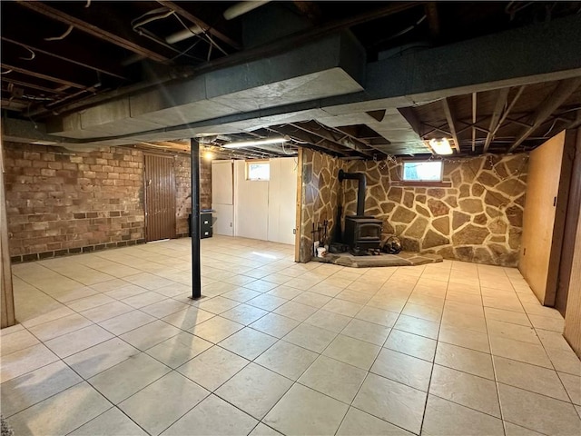 below grade area featuring a wood stove and tile patterned floors