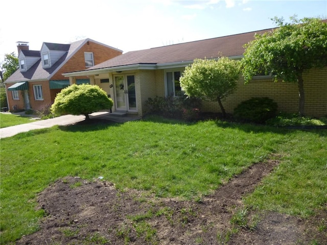 view of front of house featuring a chimney, brick siding, and a front yard