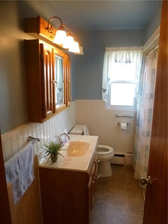 bathroom featuring a shower with curtain, vanity, toilet, a wainscoted wall, and a baseboard radiator