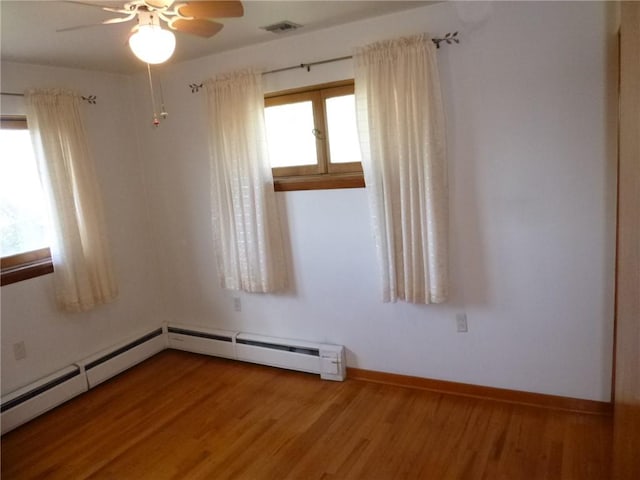 unfurnished room featuring wood finished floors, visible vents, ceiling fan, and baseboards