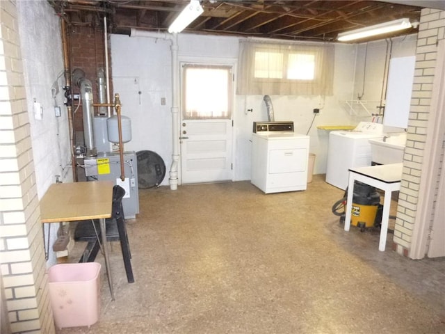 below grade area featuring light floors, a heating unit, washer and clothes dryer, and a sink
