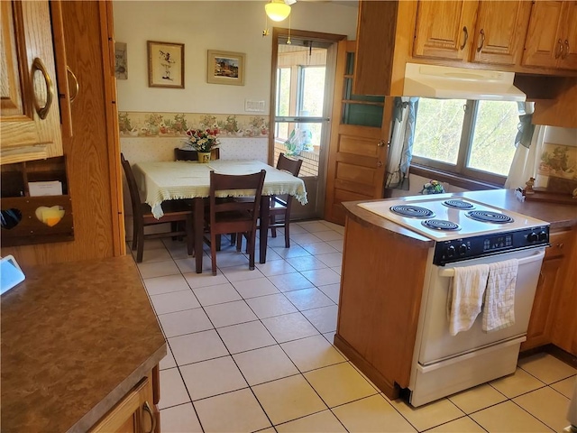 kitchen with light tile patterned floors, white electric range oven, a healthy amount of sunlight, and under cabinet range hood