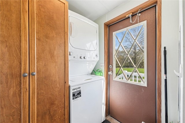 washroom featuring stacked washer / drying machine, a wealth of natural light, and laundry area