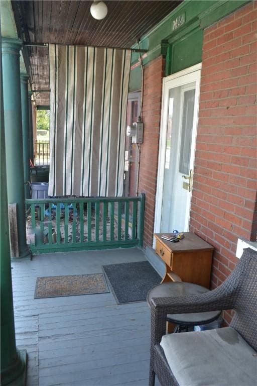 view of exterior entry featuring covered porch and brick siding