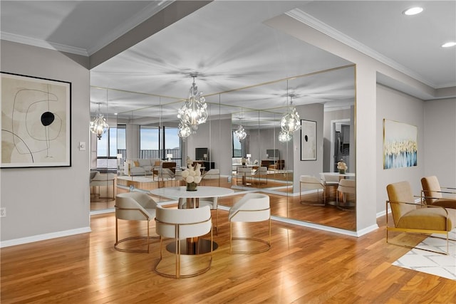 dining space featuring baseboards, ornamental molding, wood finished floors, and a notable chandelier