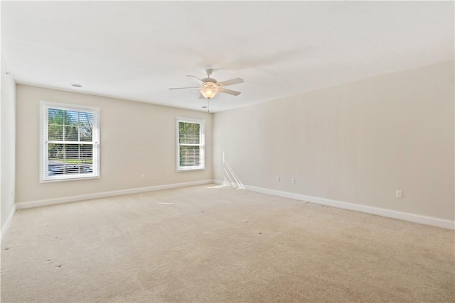 unfurnished room featuring baseboards, light carpet, and ceiling fan