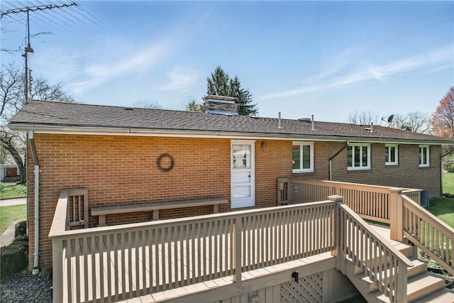 back of house featuring a wooden deck, a chimney, stairs, and brick siding