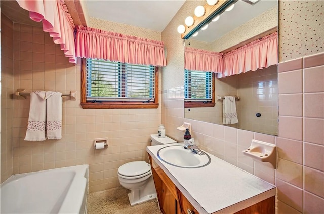 full bath with vanity, toilet, tile walls, a bathtub, and wallpapered walls