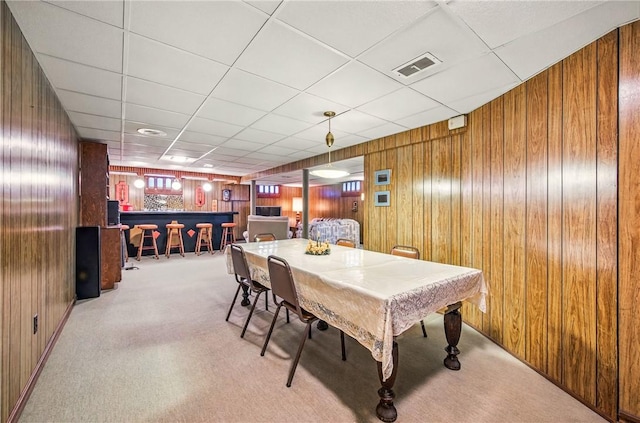 rec room featuring carpet floors, wood walls, visible vents, and a bar