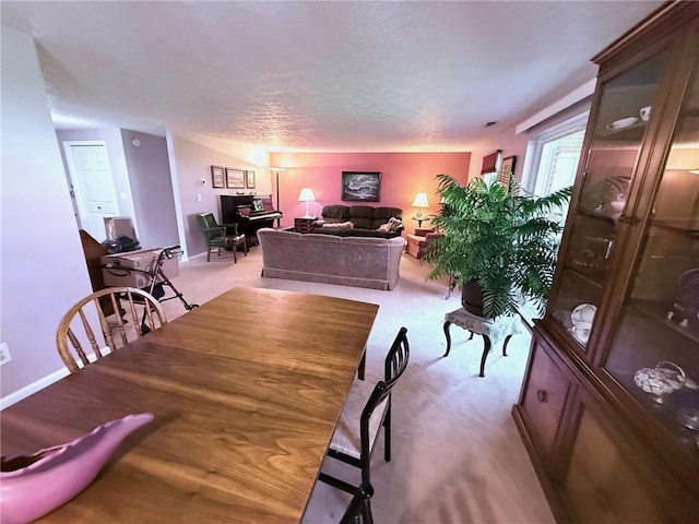 dining room featuring baseboards, a textured ceiling, and light carpet