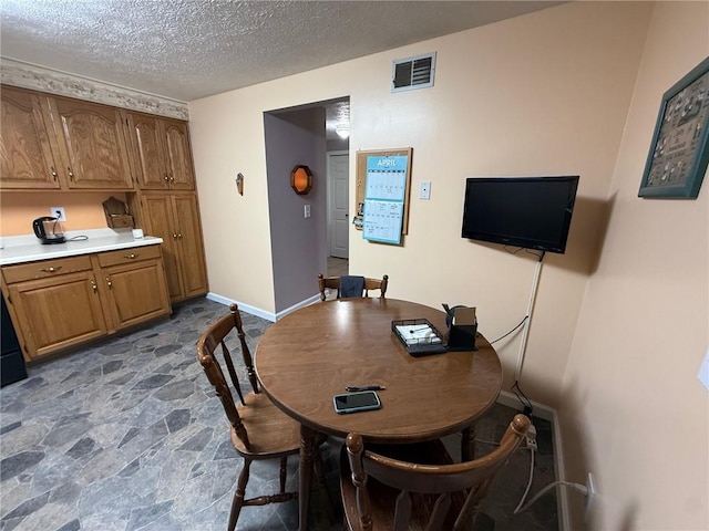 dining area with stone finish flooring, a textured ceiling, and visible vents