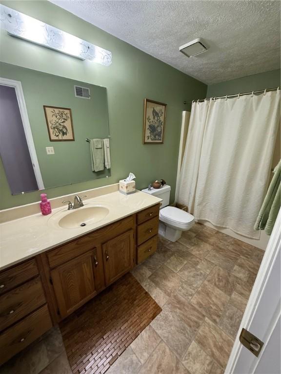 bathroom with a textured ceiling, visible vents, vanity, toilet, and a shower with shower curtain