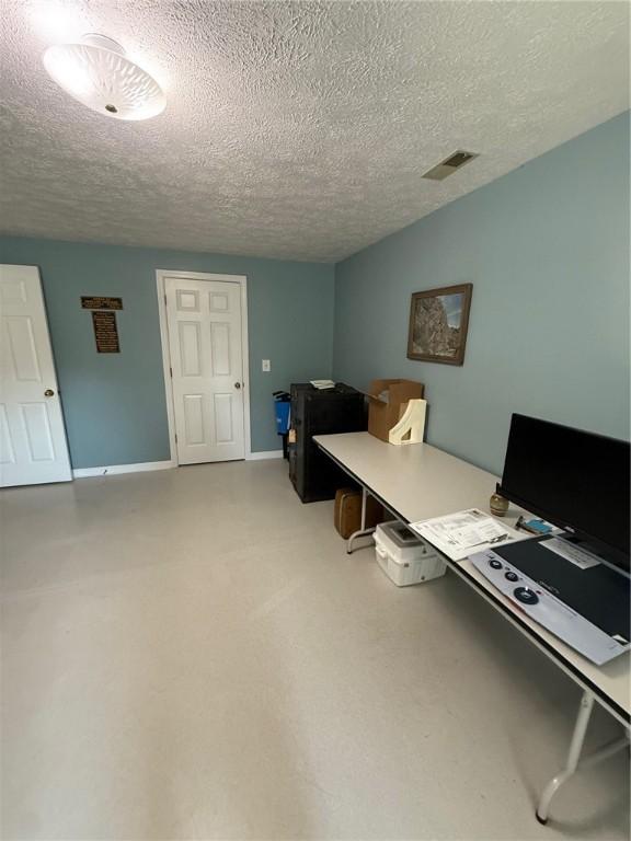 office space with baseboards, a textured ceiling, and visible vents