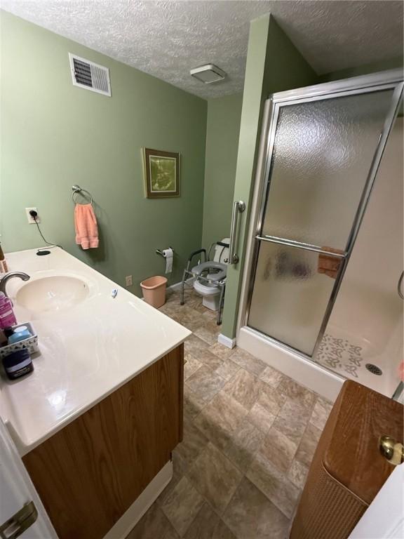 bathroom featuring visible vents, a textured ceiling, a stall shower, and vanity