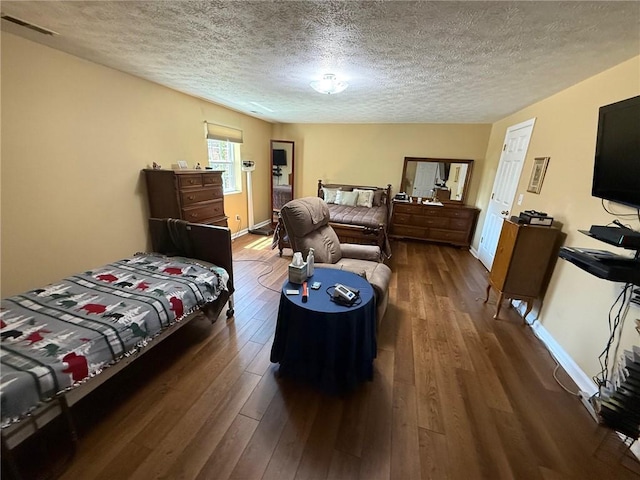 bedroom featuring baseboards, a textured ceiling, and hardwood / wood-style flooring