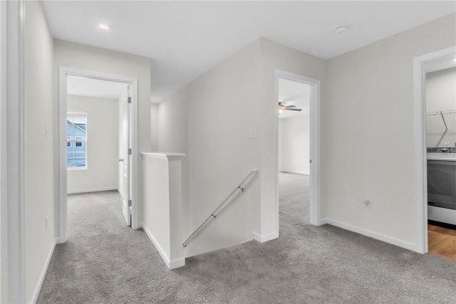 hall featuring an upstairs landing, baseboards, and carpet floors