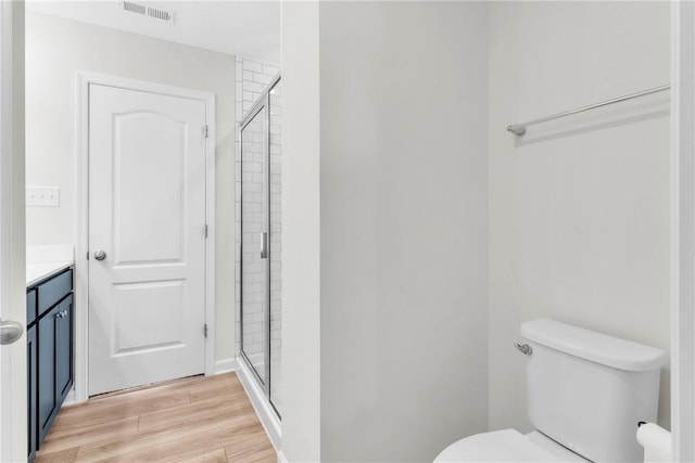 full bath featuring wood finished floors, visible vents, toilet, and a stall shower