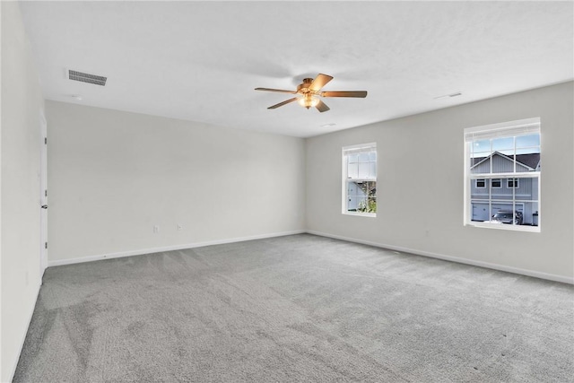 spare room with a ceiling fan, visible vents, carpet floors, and baseboards
