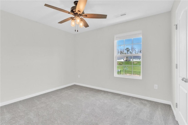 carpeted spare room with a ceiling fan, visible vents, and baseboards