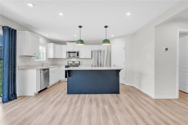 kitchen with light wood-style flooring, a sink, stainless steel appliances, light countertops, and a kitchen island