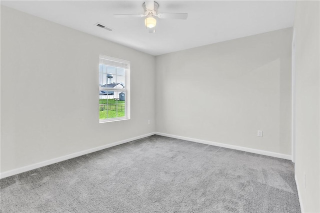 carpeted spare room featuring a ceiling fan, visible vents, and baseboards