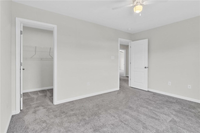 unfurnished bedroom featuring baseboards, a spacious closet, a closet, and carpet