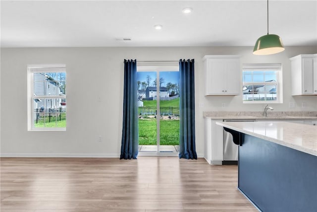 kitchen with baseboards, light stone countertops, dishwasher, light wood finished floors, and white cabinetry