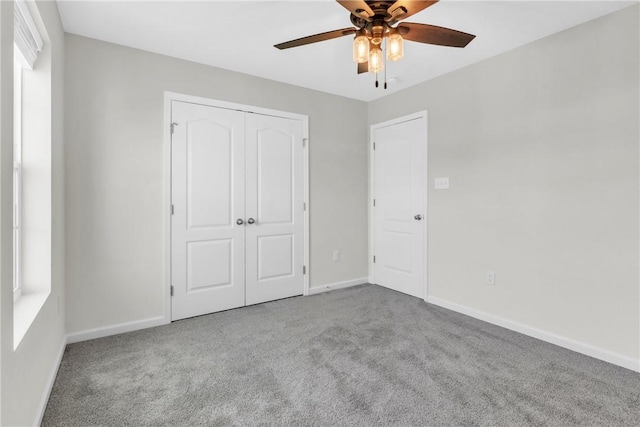 unfurnished bedroom with a closet, carpet flooring, a ceiling fan, and baseboards