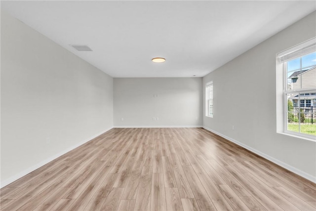 empty room featuring visible vents, light wood-style flooring, and plenty of natural light