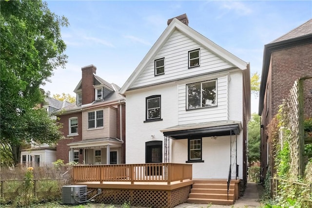 rear view of house with a wooden deck, central AC, fence, a chimney, and brick siding