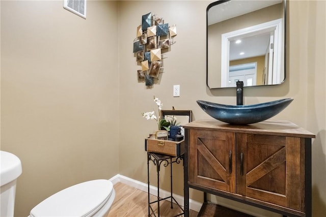 bathroom featuring visible vents, wood finished floors, baseboards, vanity, and toilet