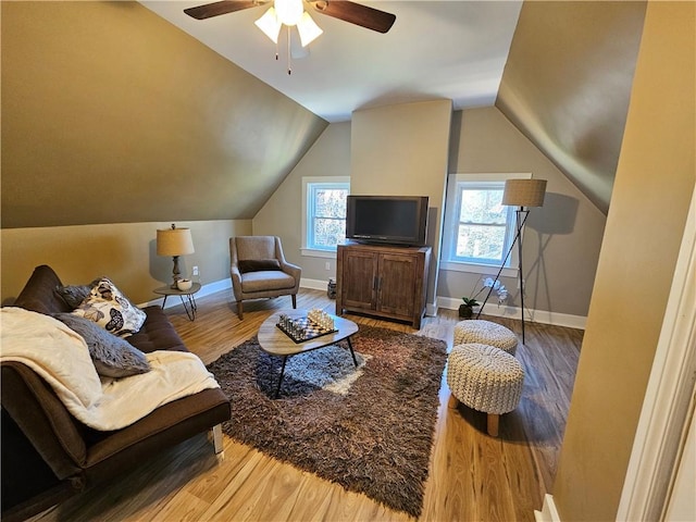 living area with a ceiling fan, baseboards, vaulted ceiling, and wood finished floors