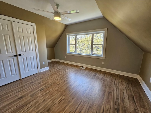 bonus room with baseboards, lofted ceiling, dark wood finished floors, and visible vents