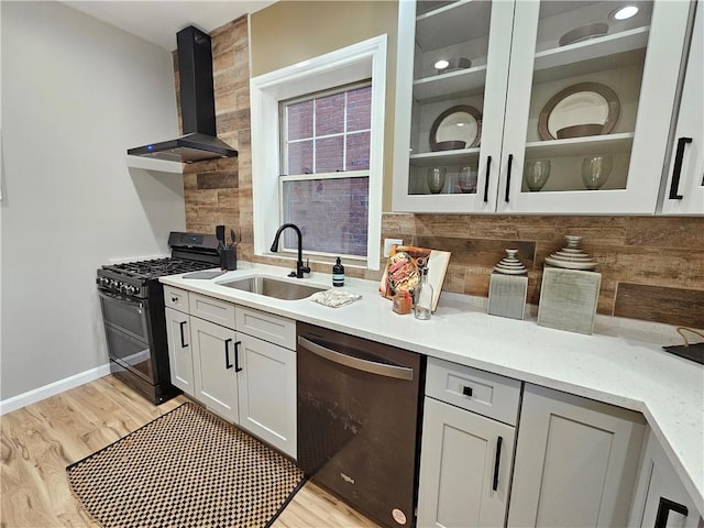 kitchen featuring black gas stove, dishwashing machine, wall chimney range hood, a sink, and backsplash