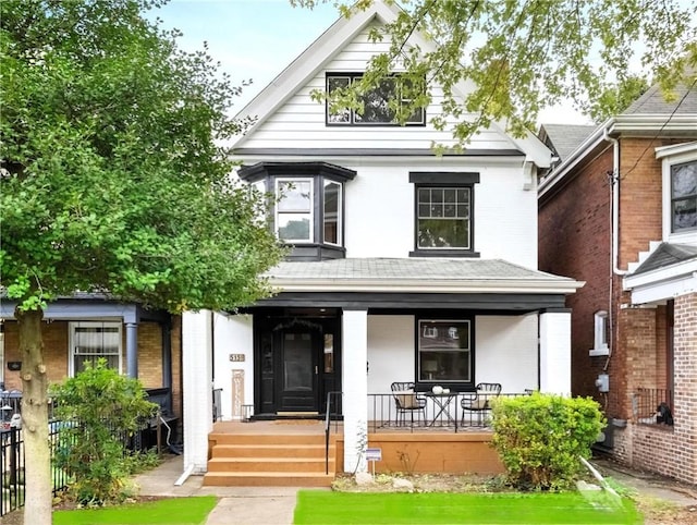 back of property featuring a porch and brick siding