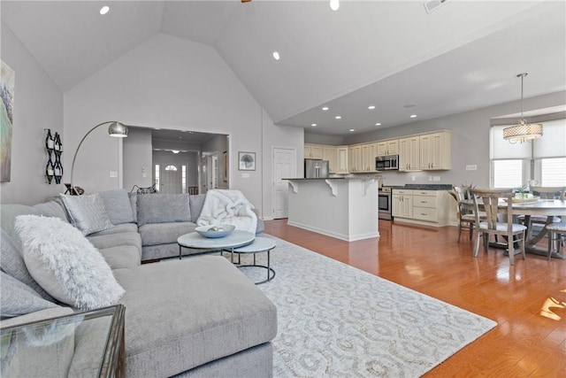 living room with high vaulted ceiling, light wood finished floors, and recessed lighting