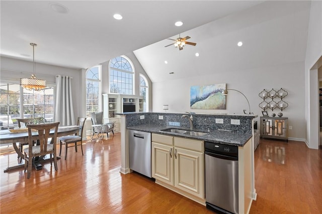 kitchen featuring cream cabinets, vaulted ceiling, dishwasher, a sink, and a ceiling fan