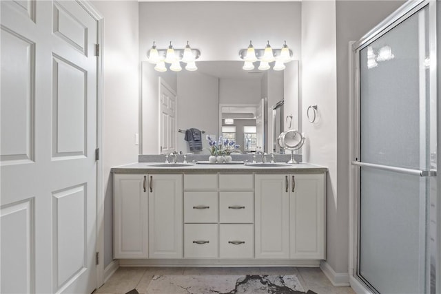 bathroom with double vanity, a sink, a shower stall, and baseboards