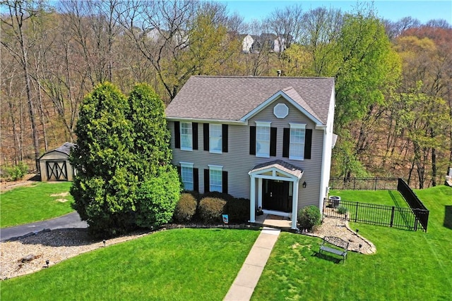 view of front facade featuring fence, a shed, and a front lawn