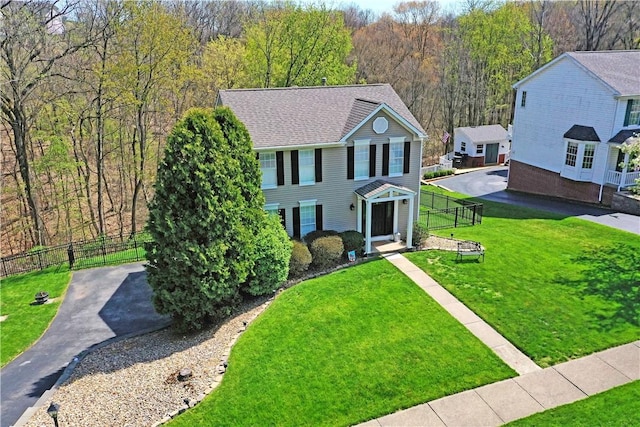 view of front of home with a wooded view, fence, and a front yard