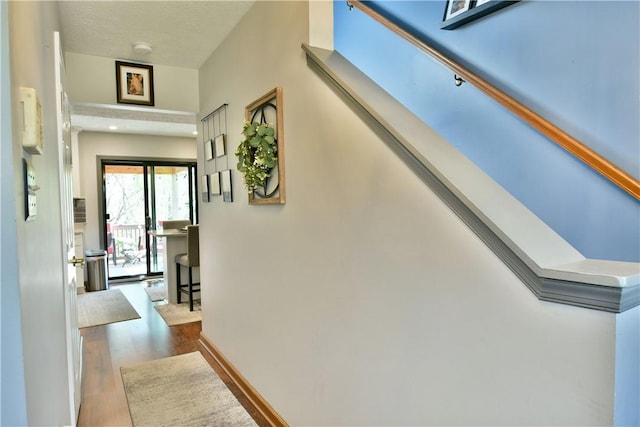 hallway with stairway, wood finished floors, and baseboards
