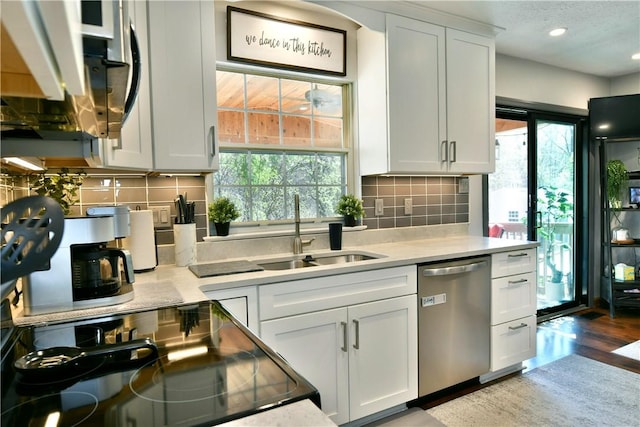 kitchen with tasteful backsplash, dishwasher, light countertops, and a sink