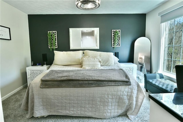 bedroom featuring an accent wall, carpet flooring, and baseboards