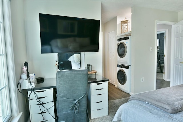 interior space with wood finished floors, stacked washing maching and dryer, and laundry area